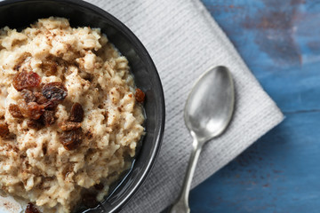 Tasty oatmeal with raisins in bowl on table - obrazy, fototapety, plakaty