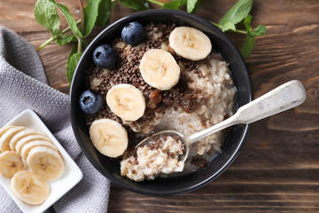 Tasty oatmeal with banana and blueberries in bowl on table
