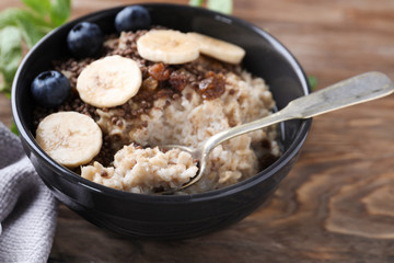 Tasty oatmeal with banana and blueberries in bowl on table