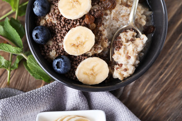 Tasty oatmeal with banana and blueberries in bowl on table