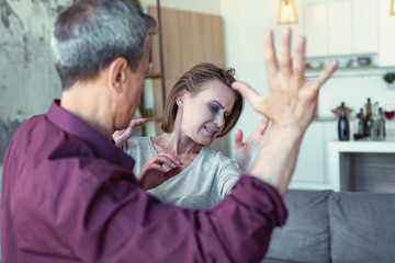 Lifting hand. Grey-haired elderly man feeling furious and angry while lifting his hand against crying wife