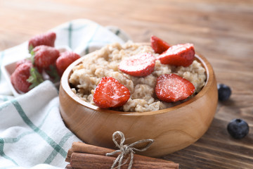 Tasty oatmeal with strawberry in bowl on table