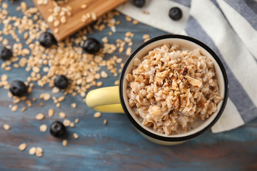 Mug with tasty oatmeal on table