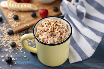 Mug with tasty oatmeal on table