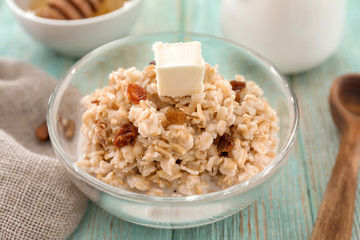 Bowl with tasty oatmeal on wooden table