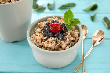 Bowl with tasty oatmeal on color table