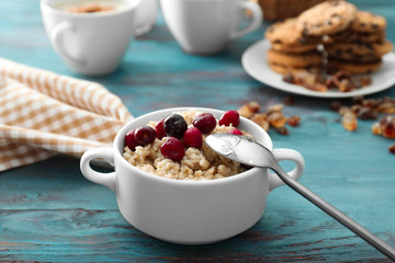 Tasty oatmeal with cherries in casserole on table