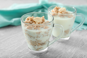 Tasty oatmeal with milk and butter in glass cup on table