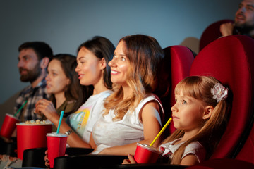 Group of friends sitting in movie theater with popcorn and drinks