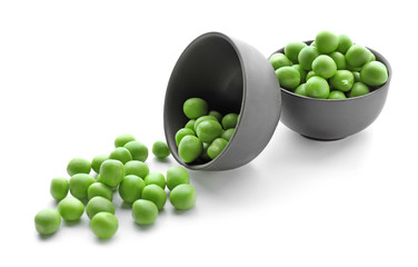Bowls with green peas on white background