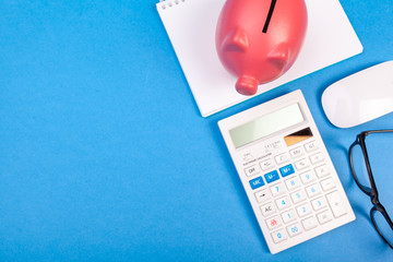 Piggy bank and calculator on color background, top view.
