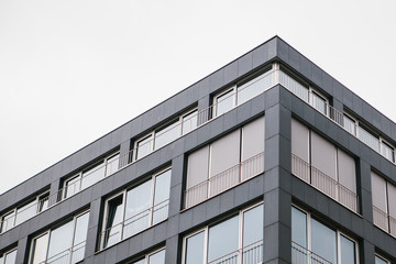 The corner of the building with many windows against the gray sky