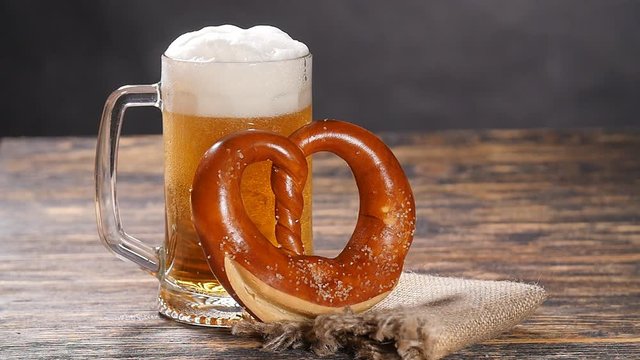 A glass of beer and pretzel on a wooden table