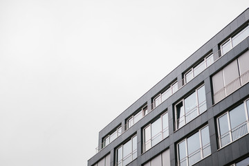 Fototapeta premium The corner of the building with many windows against the gray sky