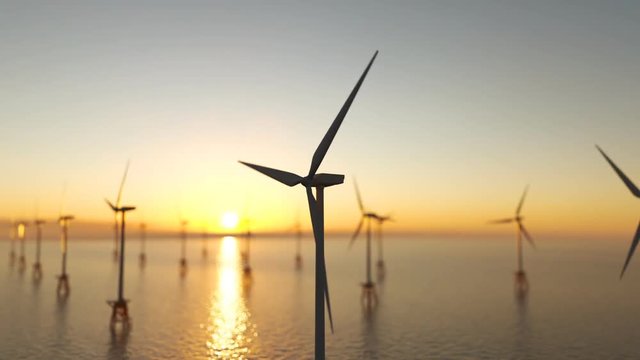 Offshore wind turbines spinning around at the sun setting marine background.
