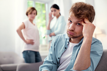 Sad mood. Portrait of a tired young man looking at you while touching his forehead