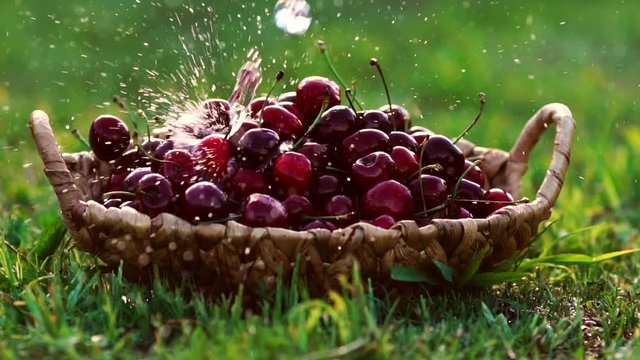 Close-up wash under running water red cherry berries in baskets standing on green grass