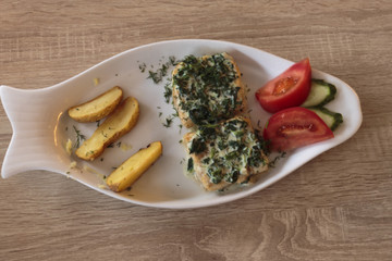 Fish dish, fried cod fillet, cod fillet fried under cheese sauce with herbs, potatoes and vegetables.