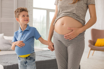Look at mother. Little cute boy smiling broadly while looking at his beautiful pregnant mother...