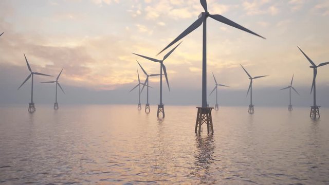 Offshore wind turbines spinning around at the sun setting marine background.
