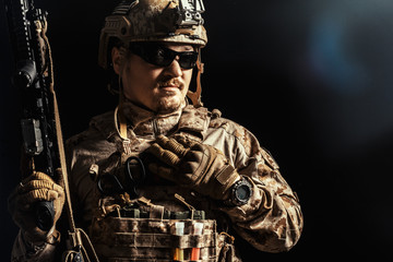 Special forces soldier with rifle on dark background