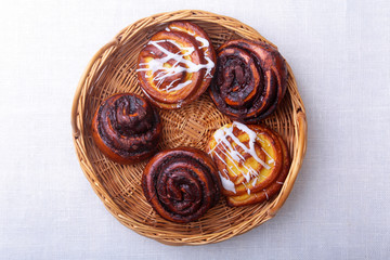 Freshly baked homemade sweet bun or sweet rolls with cinnamon in a wicker basket.