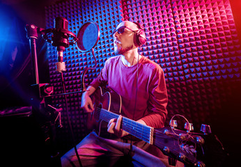 Fototapeta na wymiar The singer sings with a microphone and playing guitar in the recording studio.