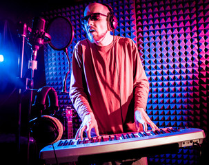 Young man playing piano in sound recording studio.