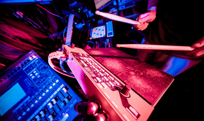 Young man playing on electric drum in sound recording studio.