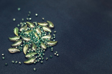 Beautiful green beads and crystals scattering on a dark background. Materials for needlework and creativity