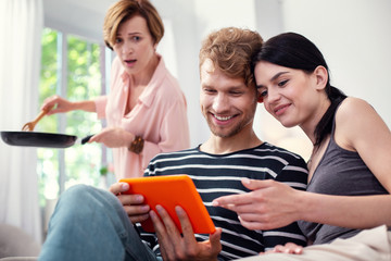 Loot at it. Cheerful nice woman pointing at the tablet screen while sitting together with her...