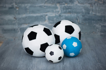 Fototapeta na wymiar Four soccer balls on a gray brick wall background