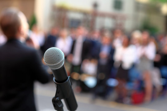 Microphone and stand in front of graduation ceremony audience against a background of auditorium