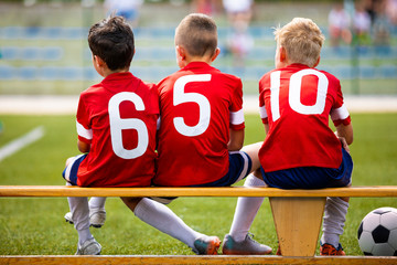 Football soccer children team. Kids substitute players sitting on a bench. Football sports...