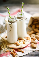 Almond and almond milk on a wooden table in the summer garden. Useful food.