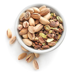 Bowl with pistachio nuts on white background