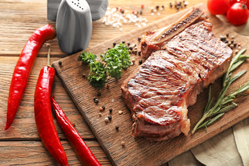 Tasty grilled meat with herbs and spices on wooden board