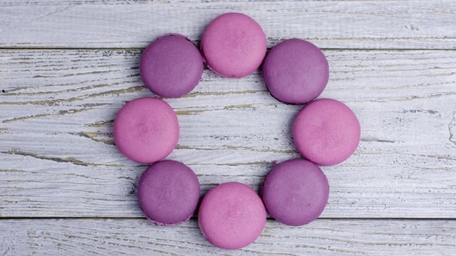 Close up stop motion of colorful macaroons on white wooden table. Loading bar of dessert. Top view.
