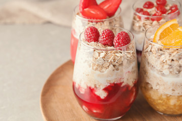 Wooden tray with tasty oatmeal desserts in glasses on light table