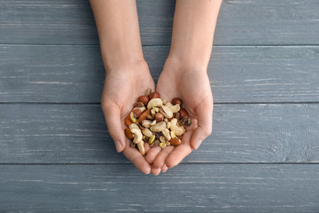 Woman holding different nuts on wooden background