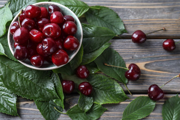 Plate with ripe cherry on wooden background
