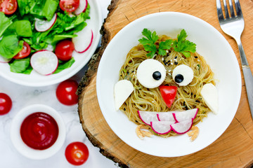 Animal shaped funny food for kids, owl pasta with sauce, vegetables and cheese