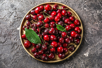 Plate with fresh ripe cherry on grunge background