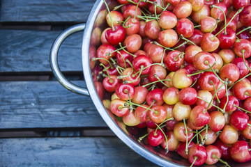 Cherries in a tin bowl on a wooden table