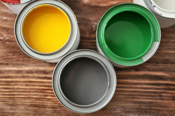 Cans of paint on wooden background