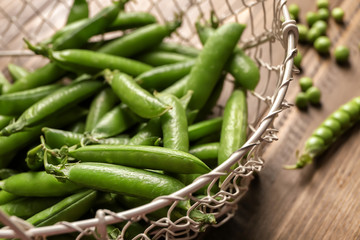 Basket with green pea pods on table, closeup