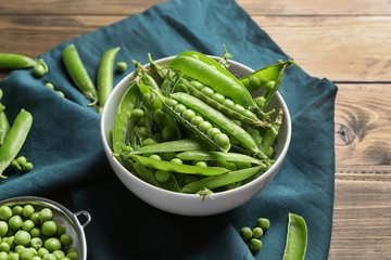 Bowl with green peas on wooden table