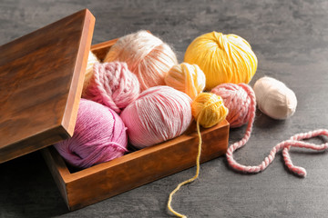 Wooden box with colorful knitting yarn on table