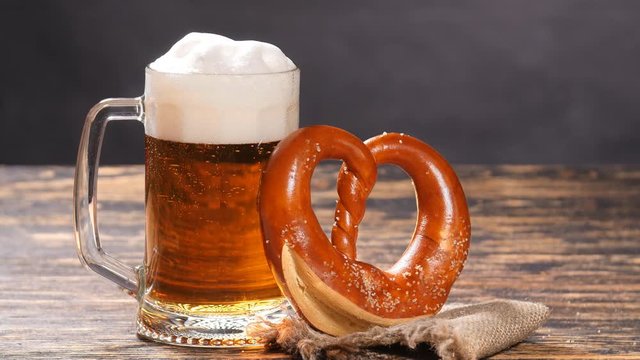 A glass of beer and pretzel on a wooden table
