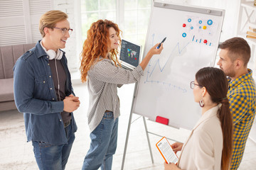 Working process. Top view of appealing four colleagues using whiteboard and working on business plan